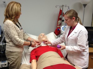 Cheryl Foote, RN (left) and Heather Kuzara, RN perform an assessment and placement of the Passy Muir® Valve on a simulation mannequin at the BAYADA Home Health Care Simulation Lab. placement of PMV on pediatric mannequin